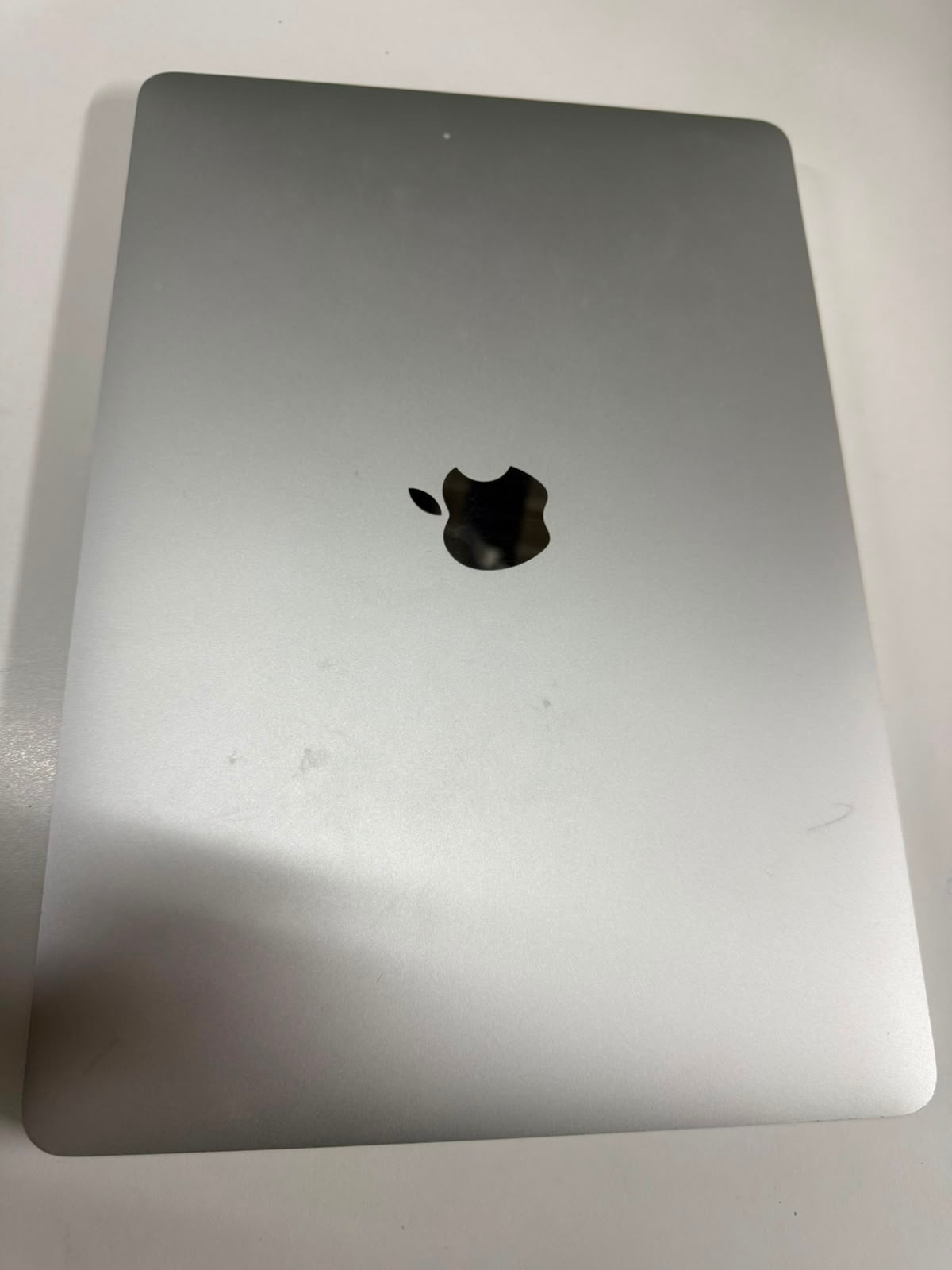 Silver pre-owned MacBook Pro closed showing Apple logo